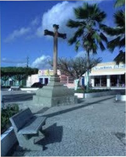 Praça urbana com cruzeiro e palmeiras em Japoatã