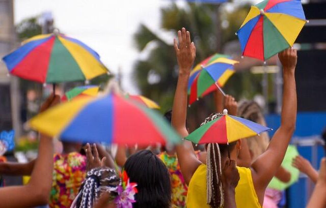 Passistas com sombrinhas coloridas no carnaval de Neópolis